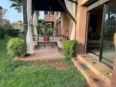 a patio with a couch and a table on a porch at Appartement élégant avec vue sur piscine jardin verdoyant et wifi ultra rapide in Marrakech