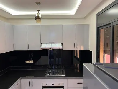 a kitchen with white cabinets and a black counter top at Gueliz Luxe Apartment in Marrakech