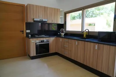 a kitchen with wooden cabinets and a stove and a window at Villa Home Orient Avec Piscine Privée 3 Chambres in Marrakech