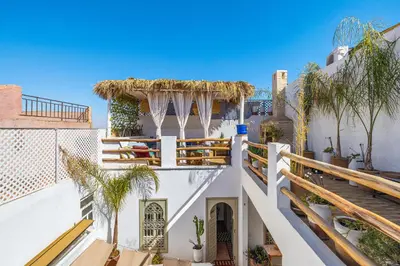 a white building with a balcony with trees at Riad Chill&Relax Dar Tayri in Marrakech