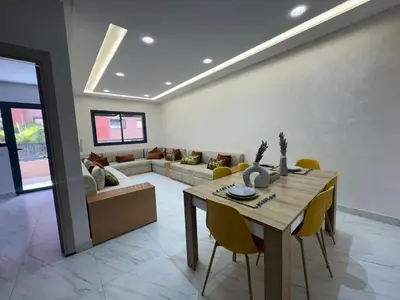 a living room with a wooden table and yellow chairs at Appartement avec piscine in Marrakech