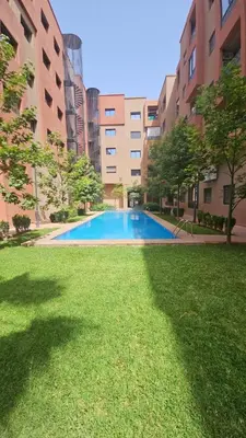 a large swimming pool in the middle of a grass field at Appartement avec piscine in Marrakech