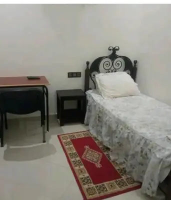 a bedroom with a bed and a desk and a table at Dar ALBIDAWI in Marrakech