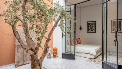 a room with a tree and a bedroom at Riad Jarco Marrakech, cœur Medina, Rooftop, bassin , Proche Place Jemaa el fna in Marrakech