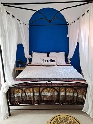 a bedroom with a bed with a blue wall at Riad Le shams in Marrakech