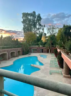 a large swimming pool with lounge chairs and a building at Somptueux appartement jardin & piscine - Hivernage in Marrakech