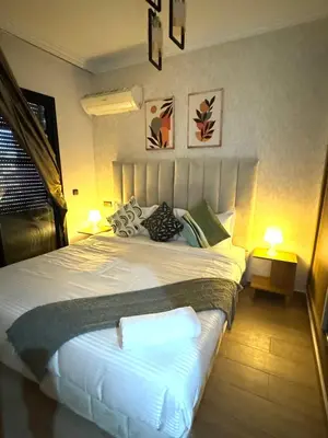 a bedroom with a large white bed with two lamps at Appartement au Centre ville Gueliz avec piscine in Marrakech
