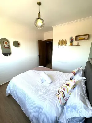 a bedroom with a white bed with pillows on it at Appartement au Centre ville Gueliz avec piscine in Marrakech