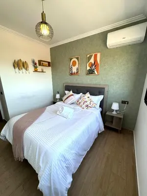 a bedroom with a large bed with white sheets at Appartement au Centre ville Gueliz avec piscine in Marrakech