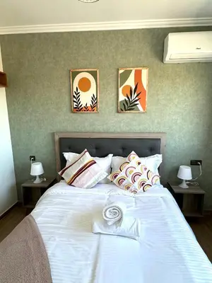 a bedroom with a white bed with three pictures on the wall at Appartement au Centre ville Gueliz avec piscine in Marrakech