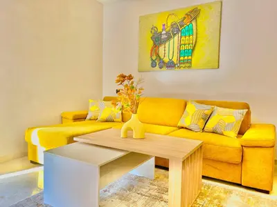 a living room with a yellow couch and a table at L'Oasis Lumineux avec Piscine et Terrasse in Marrakech