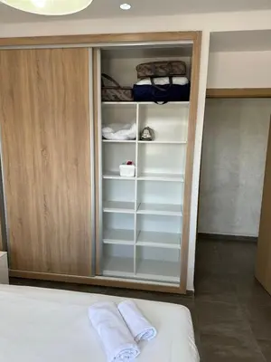 a closet with white shelves and a bed in a room at Gorgeous newly renovated apt- Near Restaurant and Shopping Center in Marrakech
