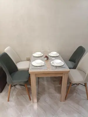 a wooden table with four chairs and plates on it at Oasis Appart in Marrakech