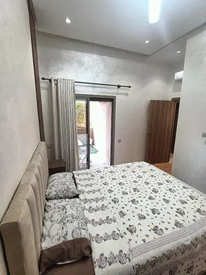 a bedroom with a bed with a flowered blanket on it at Oasis Appart in Marrakech