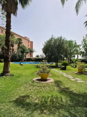 a park with palm trees and a yellow flower pot at Marrakech appartement babylon2 in Marrakech