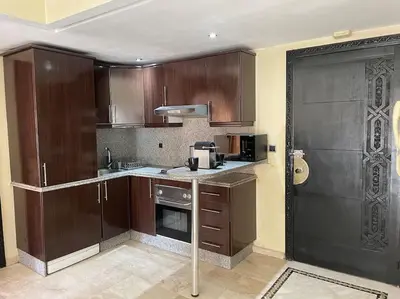 a large kitchen with wooden cabinets and a door at Guéliz appartemment Piscine à la résidence in Marrakech