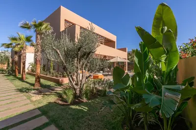 a house with trees and plants in front of it at Dar Al Ikhwa, Lodge de luxe à Marrakech in Sfiani