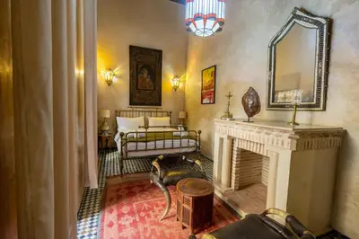 a living room with a fireplace and a bed at Riad Sarasvati & SPA in Marrakech