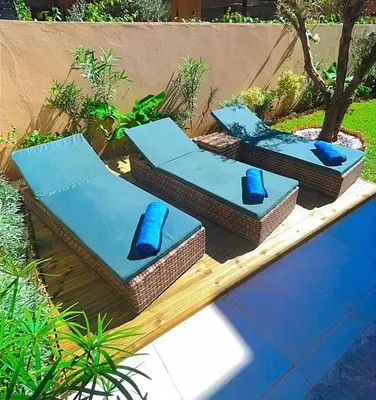three wicker chairs sitting on a table next to a pool at Villa Jassmir 5 chambres 10 min du centre piscine chauffée in Marrakech