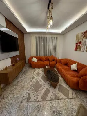 a living room with a large orange couch and a television at Luxueux Appartement-52 - Guéliz Marrakech in Marrakech