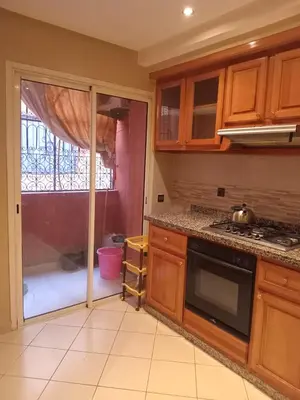 a kitchen with wooden cabinets and a stove top oven at Superbe Appartement 2 chambres à AL FADL Marrakech in Marrakech