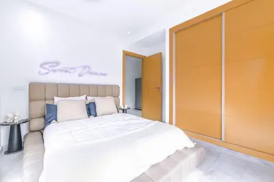 a bedroom with a large bed with white sheets and blue pillows at Fun-filled luxury city center apartment in Marrakech