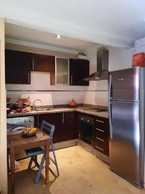 a kitchen with a table and a stainless steel refrigerator at Top Appartement 1 Rue Yves Saint Laurent for 1-2 Per- Touristes International in Marrakech