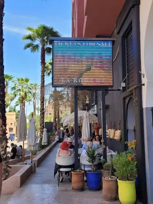 a sign outside of a restaurant with people sitting at tables at Top Appartement 1 Rue Yves Saint Laurent for 1-2 Per- Touristes International in Marrakech