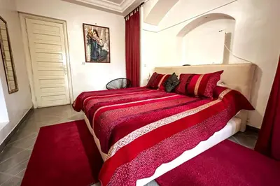 a bedroom with a large red bed with red sheets at DAR SMAWAR top piscine chauffée 15mn centre ville in El Caïd Omar