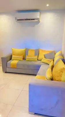 a blue couch with yellow pillows in a room at Magnifique appartement coralia in Marrakech