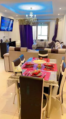 a dining table and chairs in a living room at Magnifique appartement coralia in Marrakech