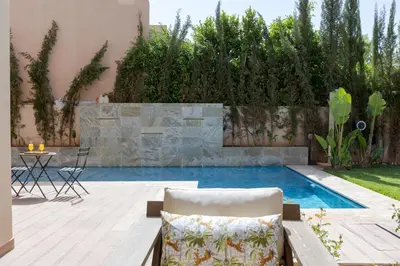 a swimming pool in a backyard with a table and chairs at Villa Golf Marrakech in Marrakech