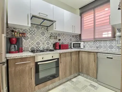 a kitchen with wooden cabinets and a stove top oven at Jade Prestigia Golf in Marrakech