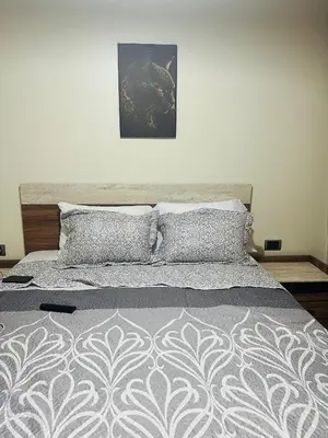 a bed with a gray and white comforter and pillows at Prestigia marrakech in Marrakech