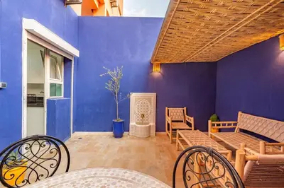 a patio with a blue wall and a table and chairs at Appartement avec terrasse et piscine in Marrakech