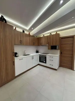 a kitchen with white counters and wooden cabinets at Bel Appartement Hivernage Gueliz in Marrakech