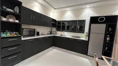 a kitchen with black cabinets and a black refrigerator at Ourika immoblier in Marrakech