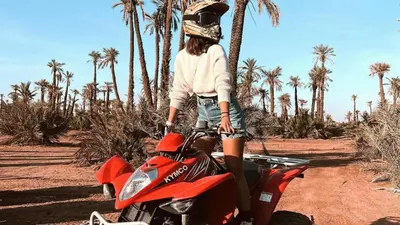 a woman is sitting on a red motorcycle at quad marrakech in Dar Caïd Layadi
