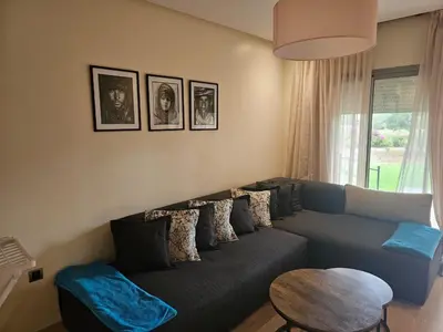 a living room with a blue couch and a table at Bel appartement avec piscine et jardin in Marrakech