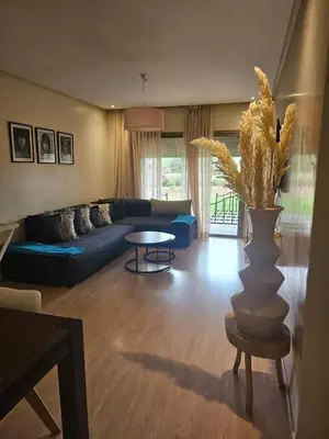 a living room with a blue couch and a table at Bel appartement avec piscine et jardin in Marrakech