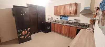 a kitchen with a black refrigerator and wooden cabinets at دوبلكس في مراكش in Marrakech