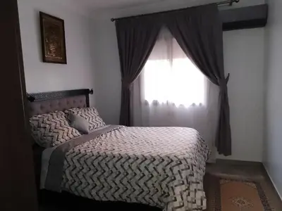 a bedroom with a bed and a window at Porte de Marrakech appartement familial avec jardin in Douar Bellouk