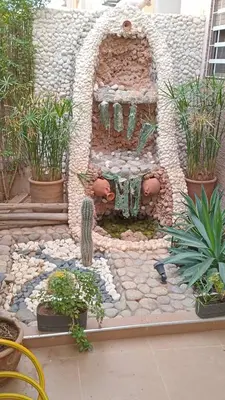 a garden with a fountain and potted plants at Porte de Marrakech appartement familial avec jardin in Douar Bellouk