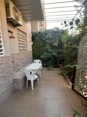 a patio with two white chairs and a table at Porte de Marrakech appartement familial avec jardin in Douar Bellouk