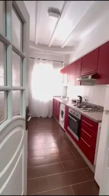 a kitchen with red cabinets and a sink and a stove at Grand Appartement Piscine Guéliz in Marrakech