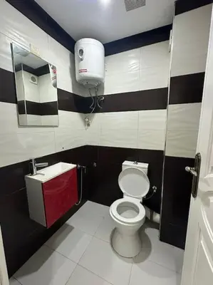 a bathroom with a toilet and a dispenser on the wall at Grand Appartement Piscine Guéliz in Marrakech