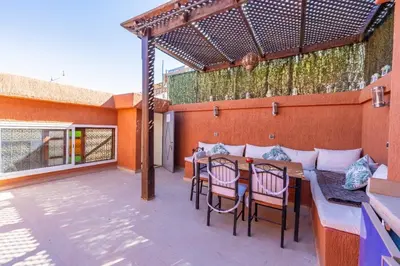 a patio with a table and chairs on a deck at Riad Malika in Marrakech