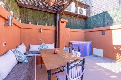 an outdoor patio with a wooden table and chairs at Riad Malika in Marrakech