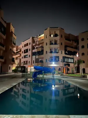 a swimming pool in front of a building at night at Premuim village Marrakech in Marrakech