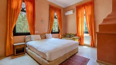 a bedroom with a bed and windows with orange curtains at la villa du golf in Sfiani